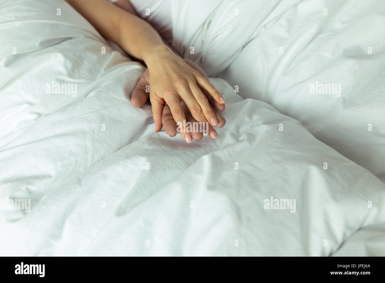 Close-up Teilansicht des Paares in der Liebe im Bett liegend und Hand in Hand Stockfoto