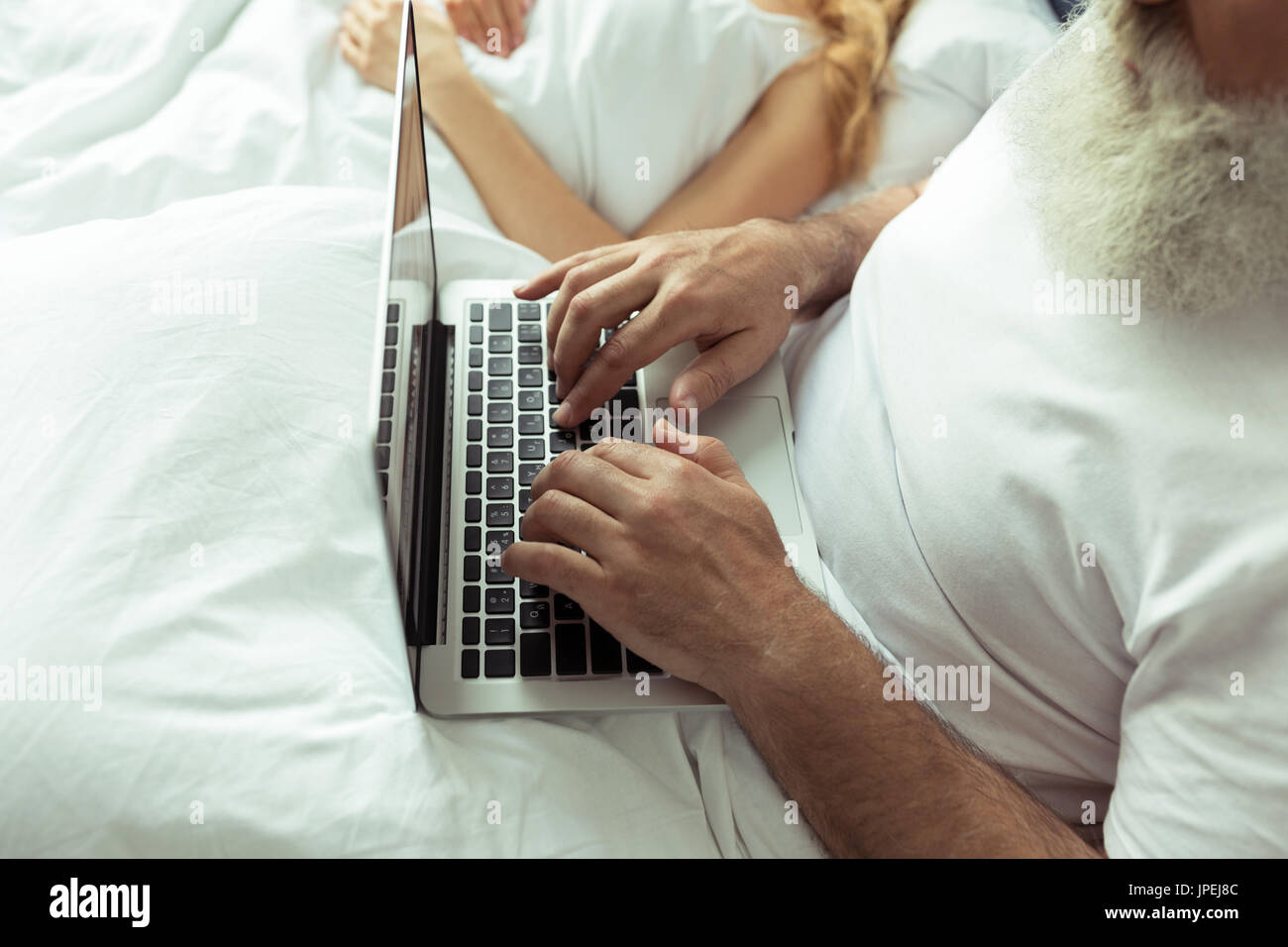Beschnitten, Schuss von reifes Paar ruhen im Bett, Mann mit laptop Stockfoto