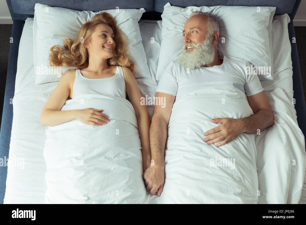 Draufsicht der lächelnde paar im Bett liegend und Hand in Hand zu Hause Stockfoto