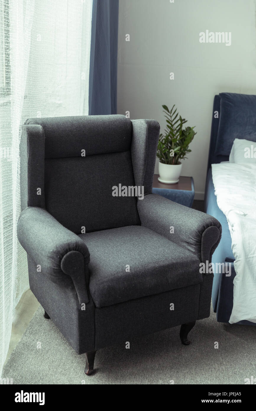 moderne dunkle gepolsterte Sessel in traditionellen helle Schlafzimmer Stockfoto