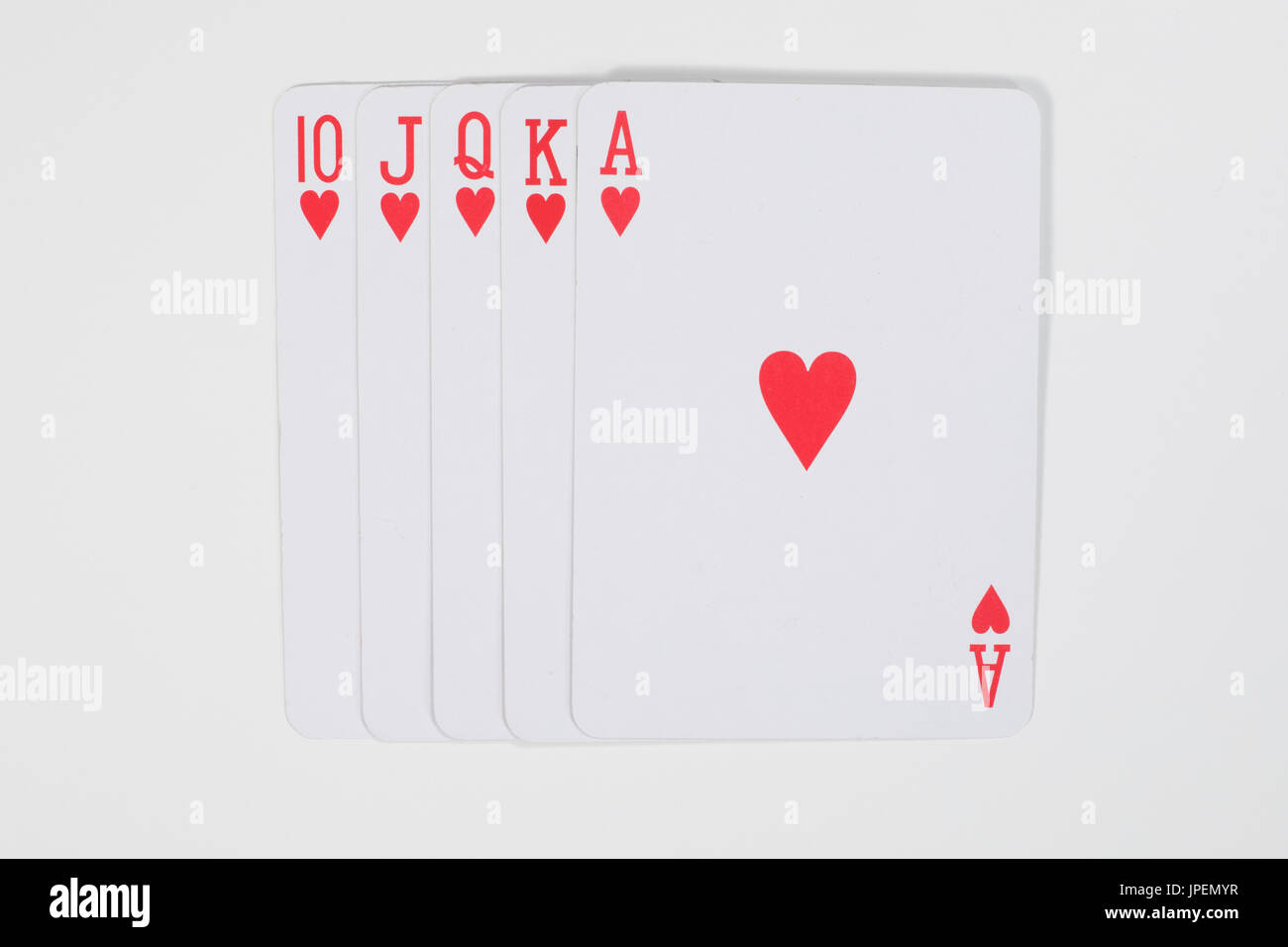 Höchste Karte Gewinnerhand beim Poker mit einem geraden Royal Flush in Herzen von oben gesehen auf weiß in einem Glücksspiel-Konzept Stockfoto
