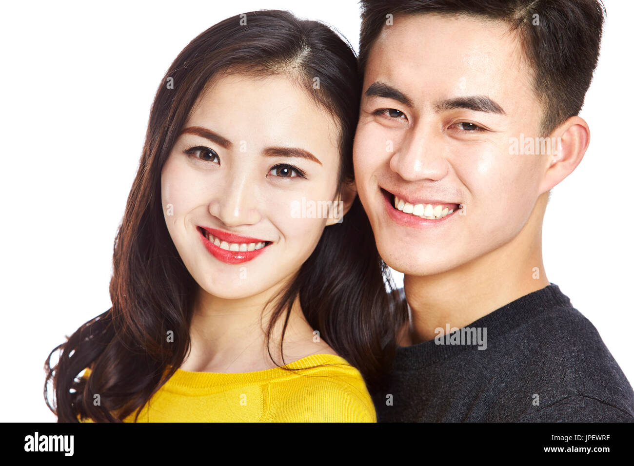 Studio-Porträt der jungen asiatischen paar Kamera Lächeln auf den Lippen, den Kopf gedreht, isoliert auf weißem Hintergrund zu betrachten. Stockfoto
