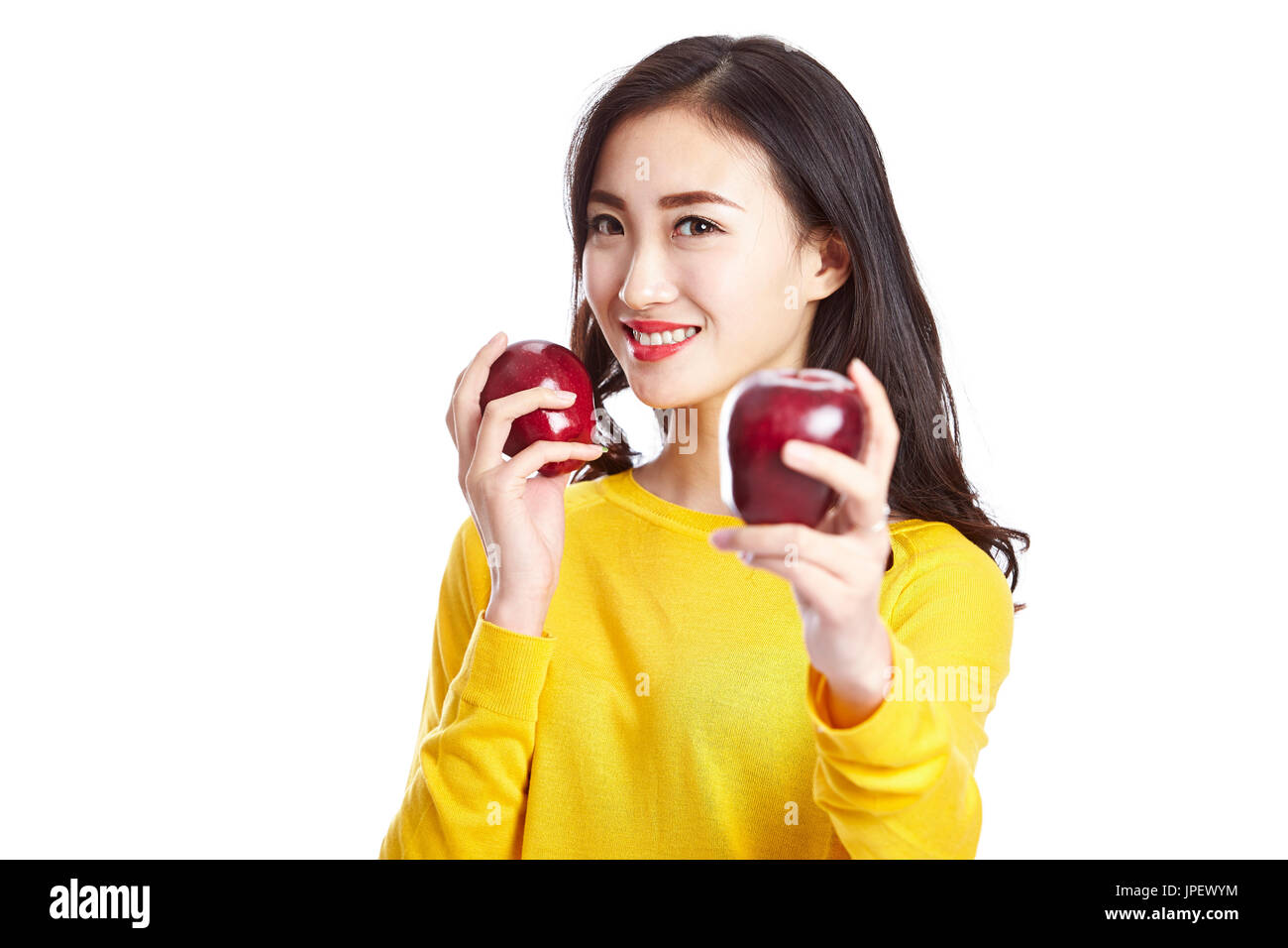 junge und schöne Asiatin zeigt zwei rote Äpfel, isoliert auf weißem Hintergrund. Stockfoto