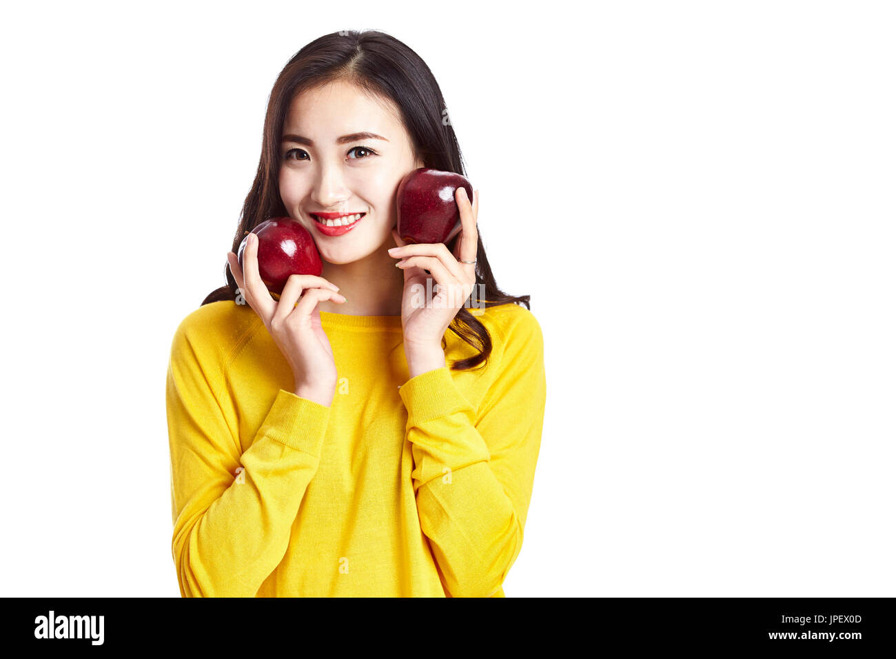 junge und schöne Asiatin zeigt zwei rote Äpfel, isoliert auf weißem Hintergrund. Stockfoto