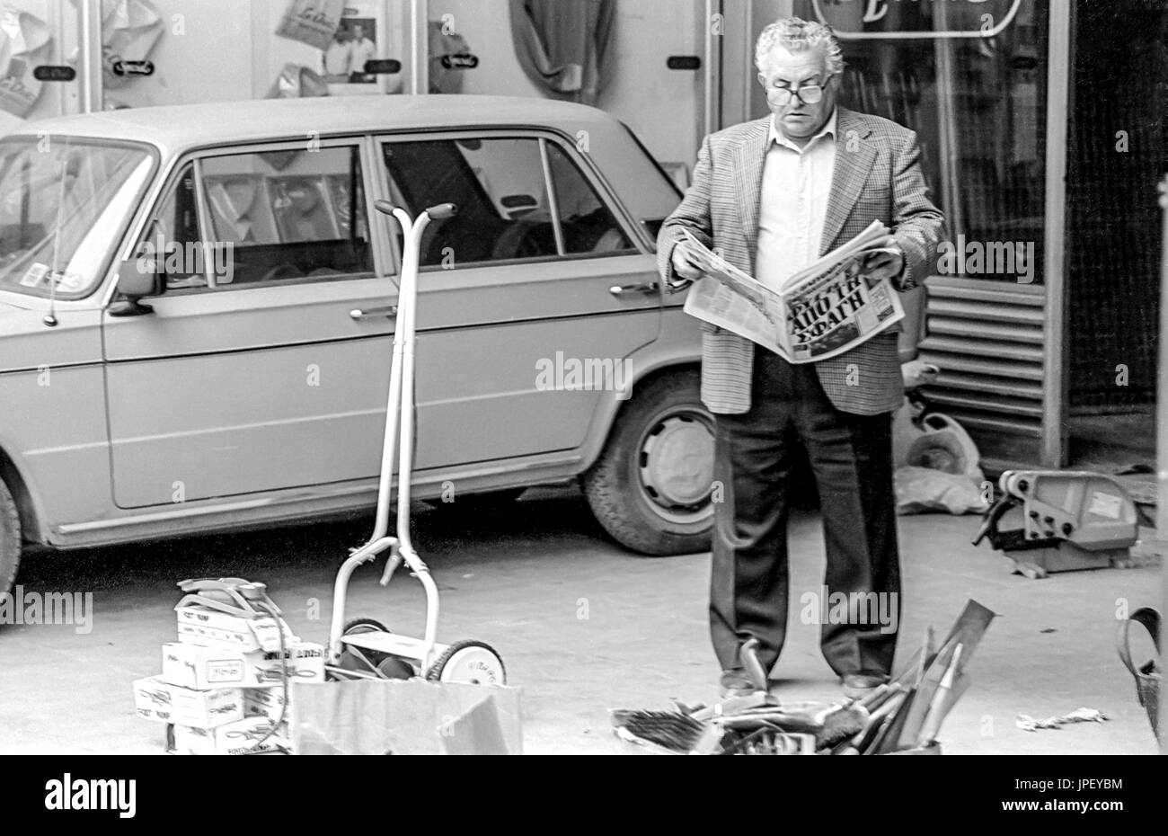 Ein Mann liest eine Zeitung auf der Straße in Athen im Jahr 1986 Stockfoto
