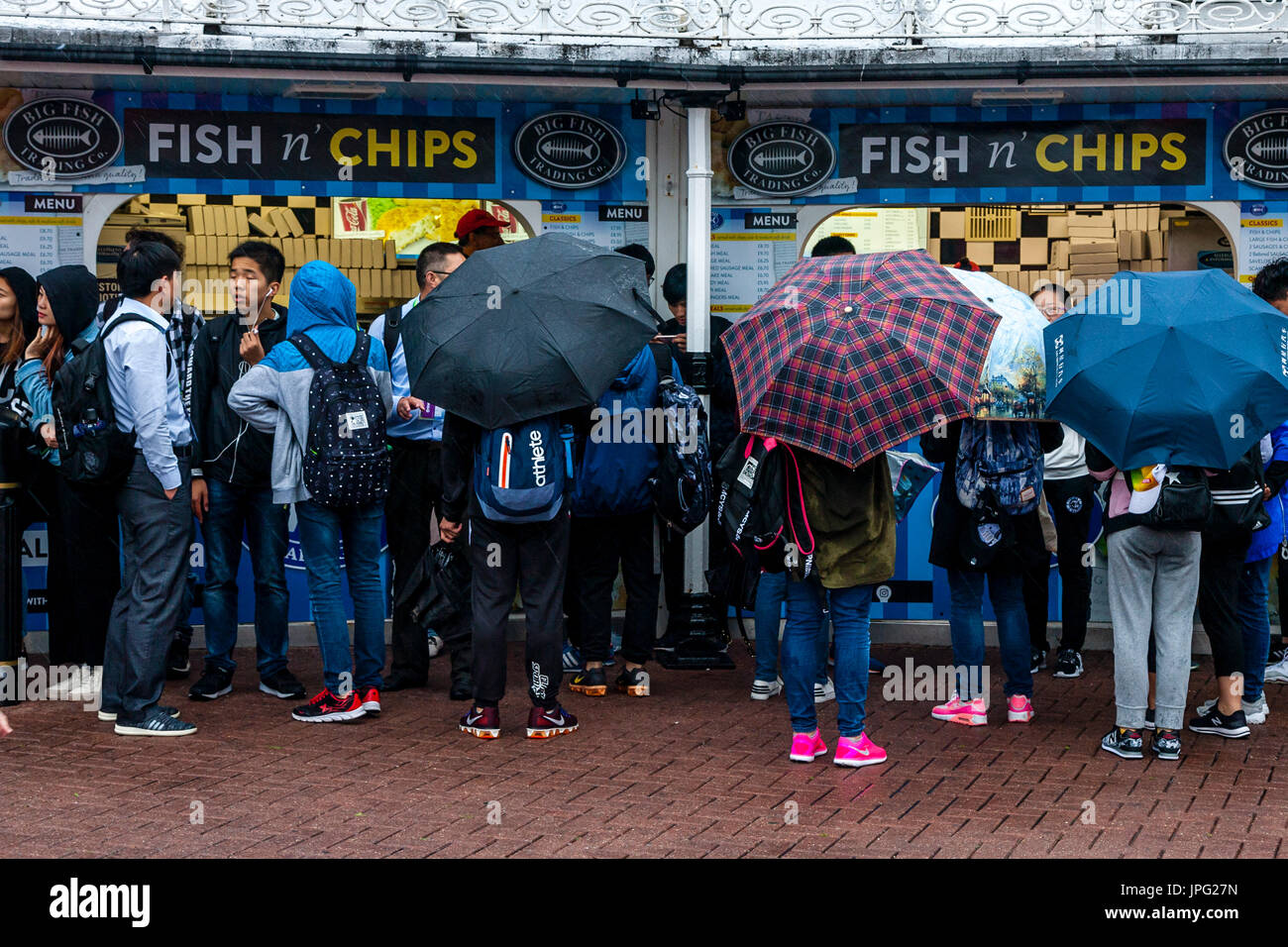 Brighton, UK. 2. August 2017. Großbritannien Wetter. Eine Gruppe von jungen chinesischen Touristen Warteschlange im Regen, Fish &amp; Chips auf Brighton Seafront, Brighton, East Sussex, UK zu kaufen. Bildnachweis: Grant Rooney/Alamy Live-Nachrichten Stockfoto