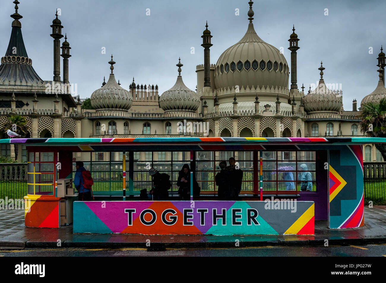 Brighton, UK. 2. August 2017. Großbritannien Wetter. Menschen Schutz vor dem Regen in einer bunten Wartehalle, Brighton, East Sussex, UK. Die Haltestelle wurde vorübergehend für das kommende Wochenende in Brighton Pride gemalt. Bildnachweis: Grant Rooney/Alamy Live-Nachrichten Stockfoto