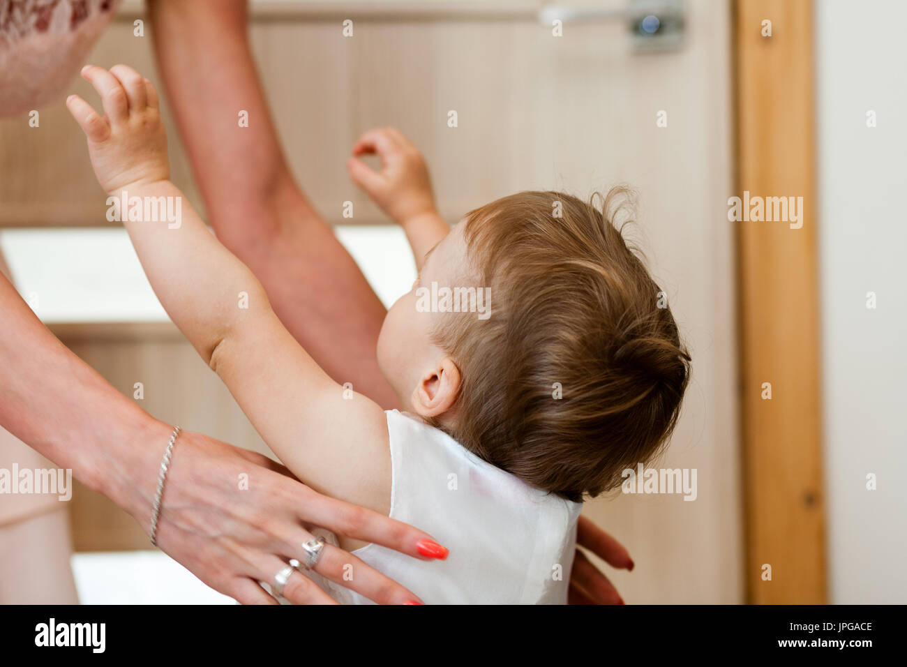 Baby von Mutter mit weißen zeremoniellen Kleidung vorbereitet. Taufe Kleidung. Taufe Stockfoto