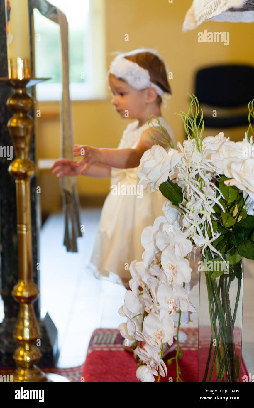 Baby von Mutter mit weißen zeremoniellen Kleidung vorbereitet. Taufe Kleidung. Taufe Stockfoto