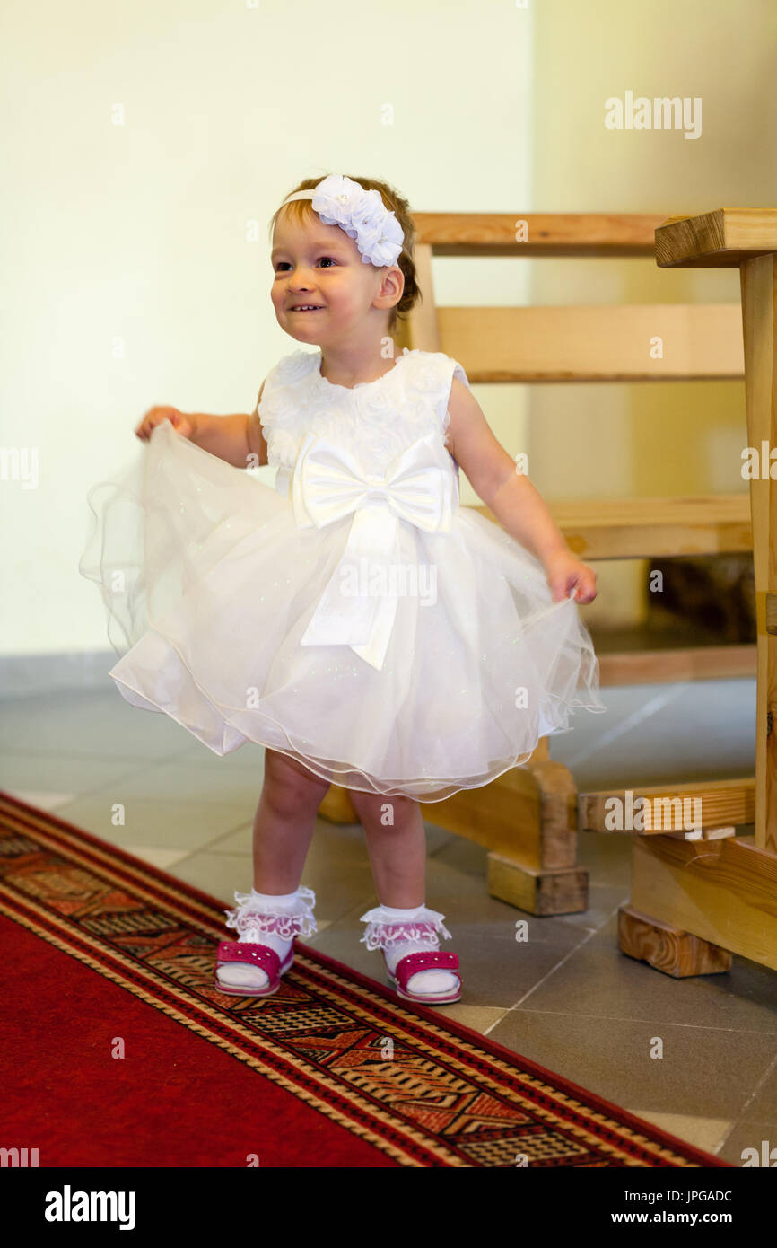 Baby von Mutter mit weißen zeremoniellen Kleidung vorbereitet. Taufe Kleidung. Taufe Stockfoto