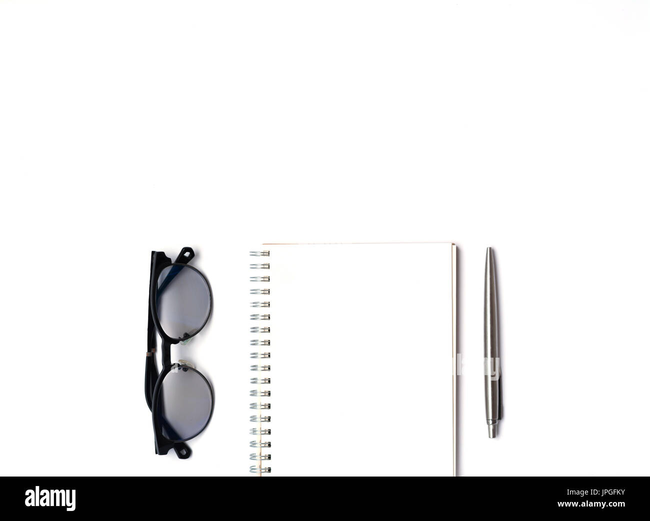 Draufsicht der modernen weißen Schreibtisch Bürotisch mit Notizbuch, Stift und Gläser mit Textfreiraum, lag flach. Stockfoto