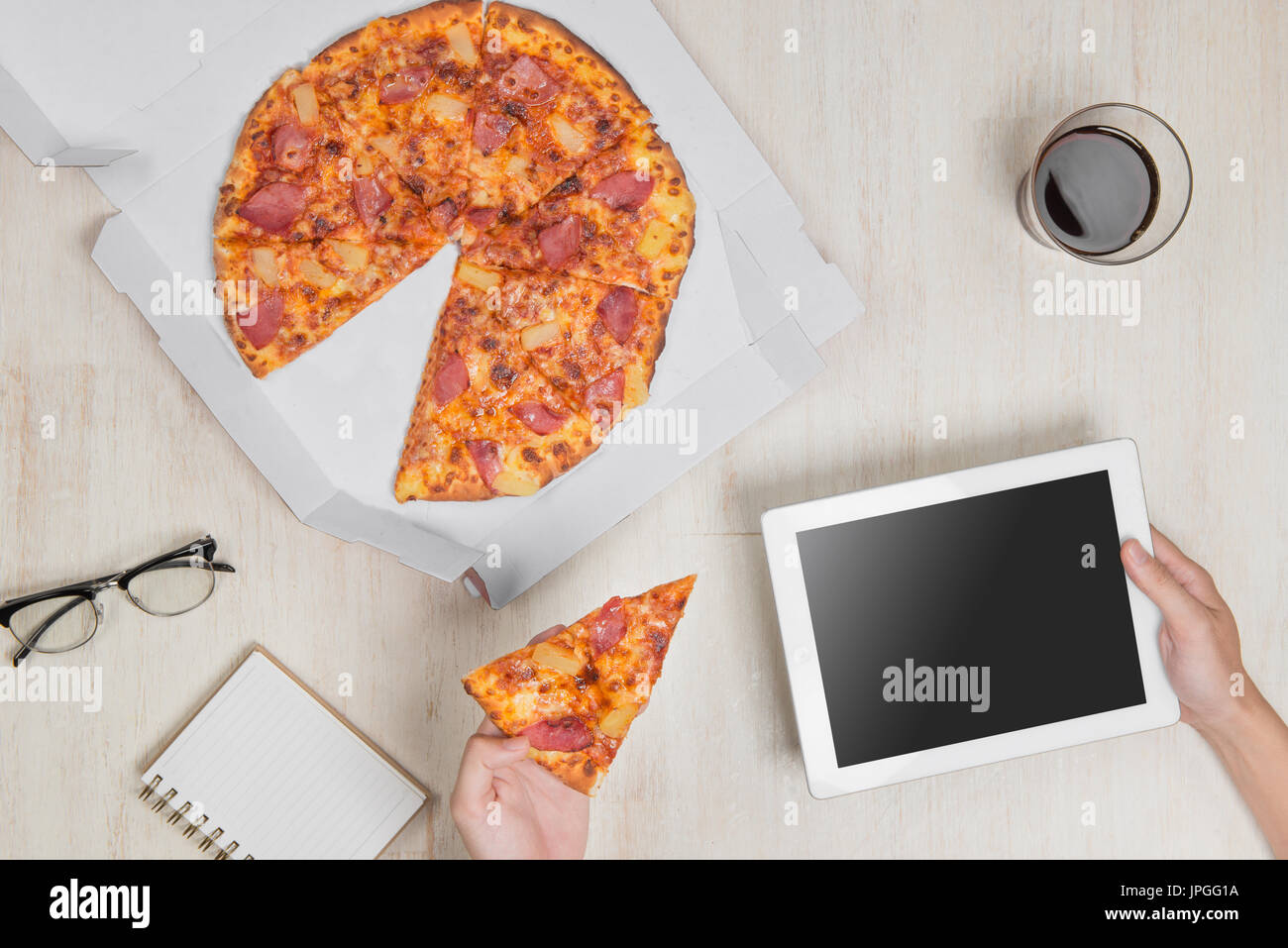 Top View-Bild. Schnelle Pizza-Lieferservice. Mann Essen und verwenden eines tablet Stockfoto