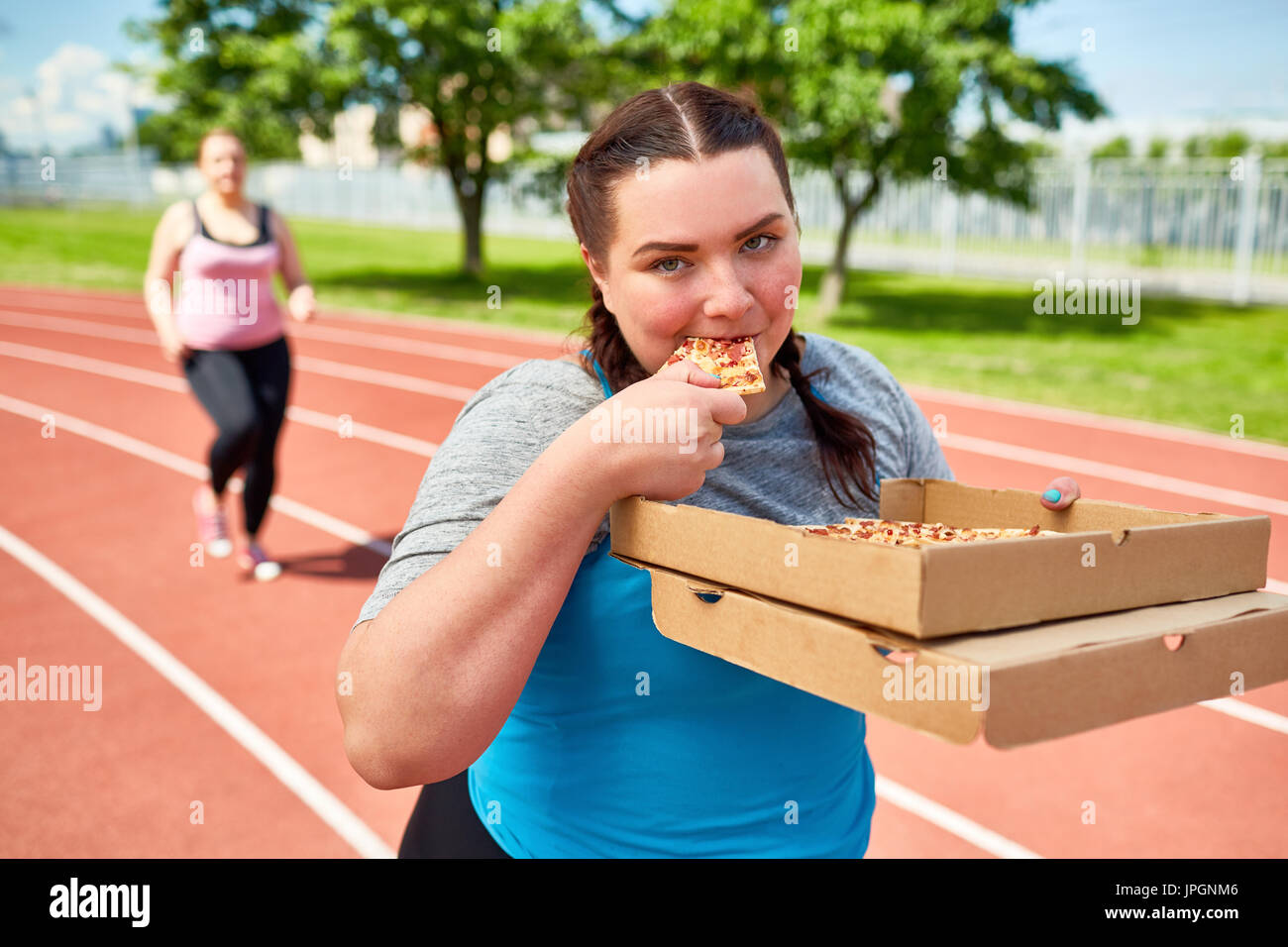 Mit zwei Kartons von lecker Pizza zum mitnehmen, Essen eine während des Trainings Fett junge weibliche Stockfoto