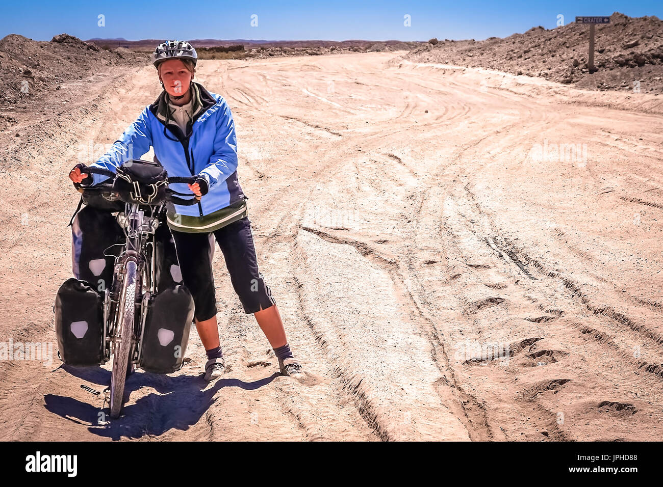 Frau Radrennfahrer kämpfen und schieben ihr Fahrrad auf Wellpappe Sandweg im Altiplano in Bolivien Stockfoto