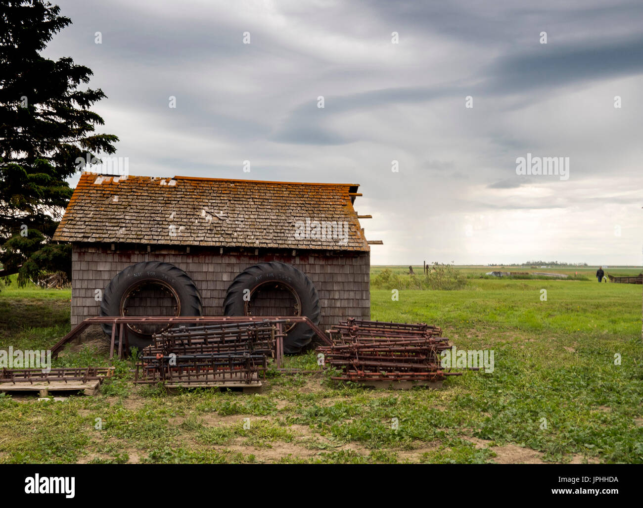 Traktorreifen auf ein altes Bauernhaus in grünen Feldern: Stockfoto