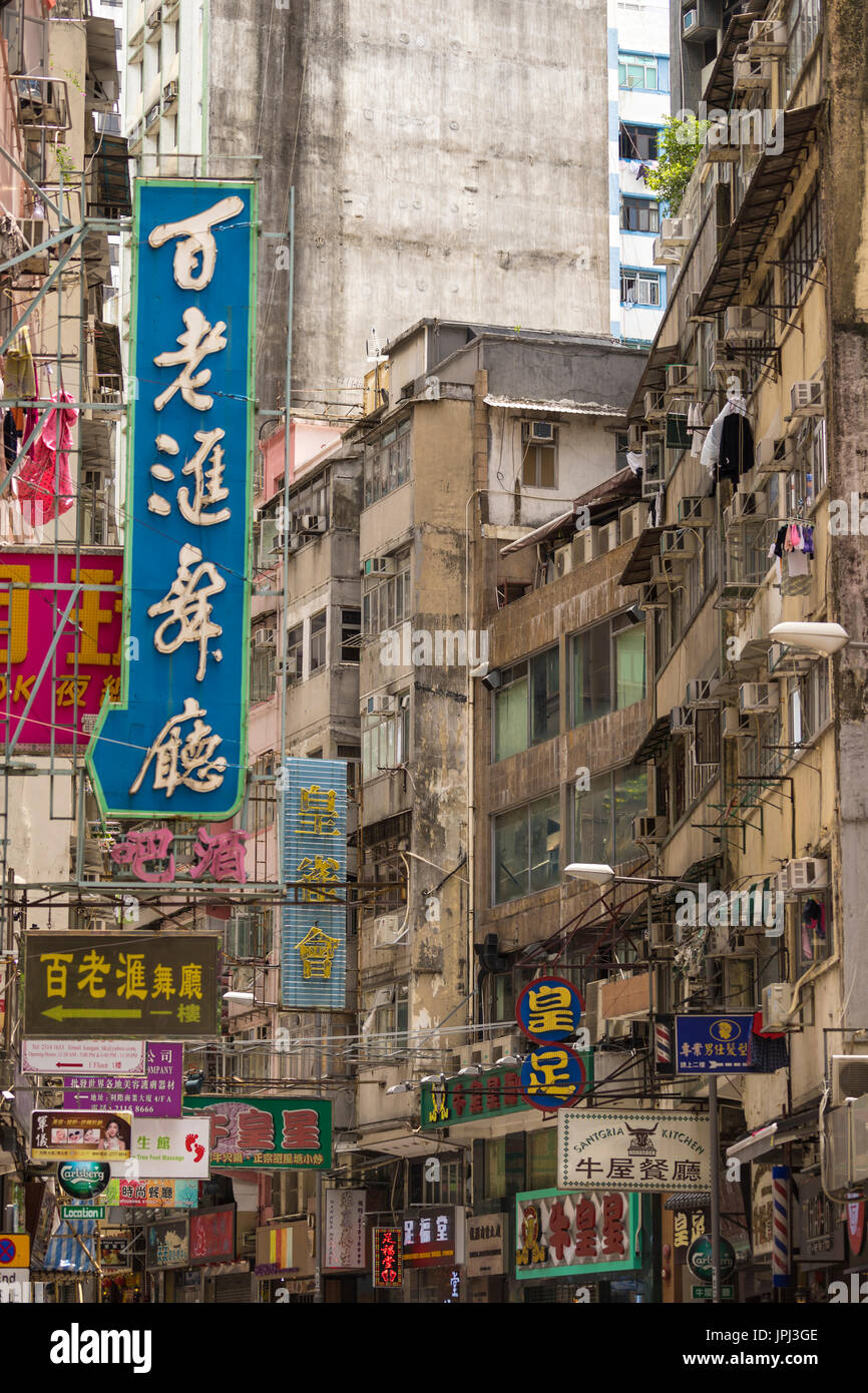 Kakophonie von chinesischen und englischen Schilder an heruntergekommenen Gebäuden im kaufmännischen Bereich von Kowloon, Hong Kong Stockfoto
