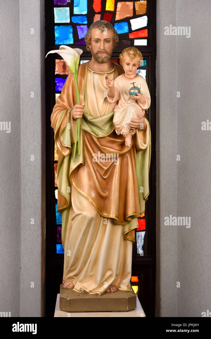Statue des Heiligen Josef fördern Vater hält Sohn Jesus und Lilien am Glasfenster in Saint Roch katholische Kirche Toronto Kanada Stockfoto