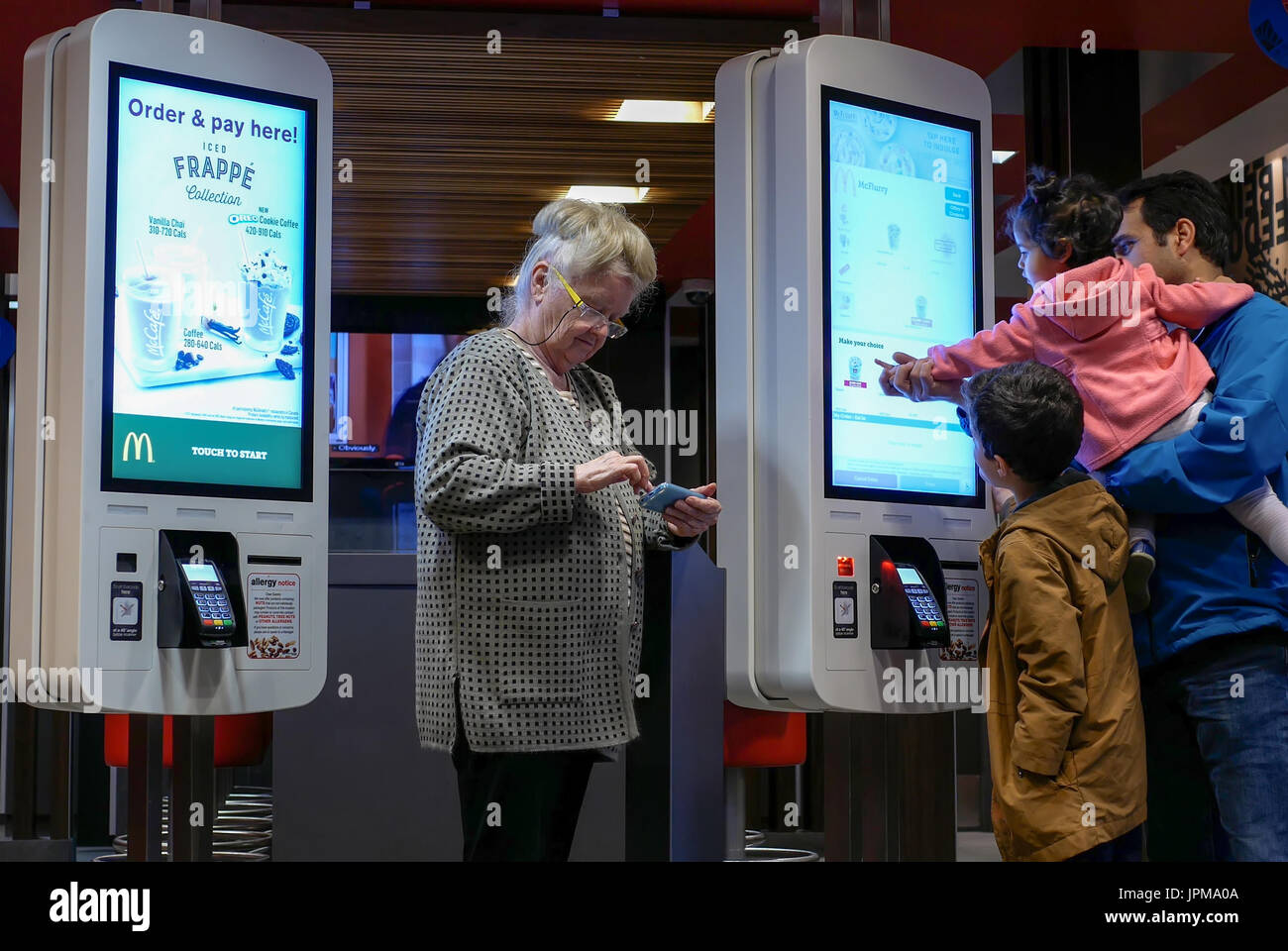 Coquitlam, BC, Kanada - 11. April 2017: Familie beim Self Check-out Maschine und alte Dame spielen Handy im Mcdonalds Restaurant Essen bestellen Stockfoto