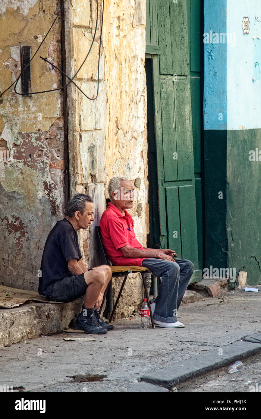 Zwei Männer haben ein Gespräch auf dem Bürgersteig in Trinidad, Kuba sitzen. Stockfoto