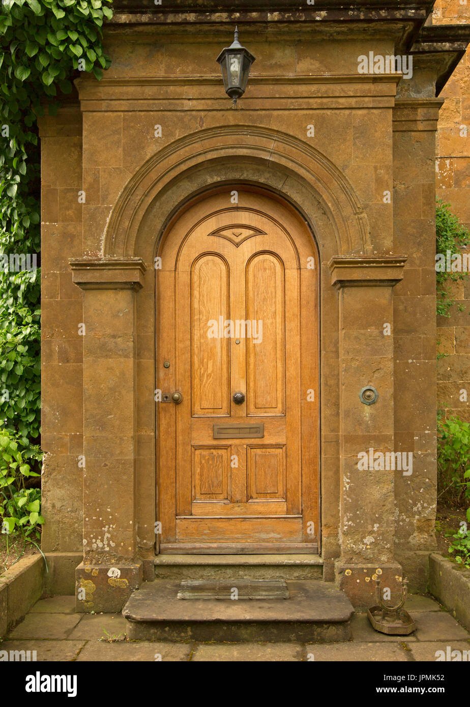Elegant geschnitzten gewölbten Golden braunen Holztür in reich verzierten steinernen Eingang zur Englischen cottage in Adderbury, England Stockfoto