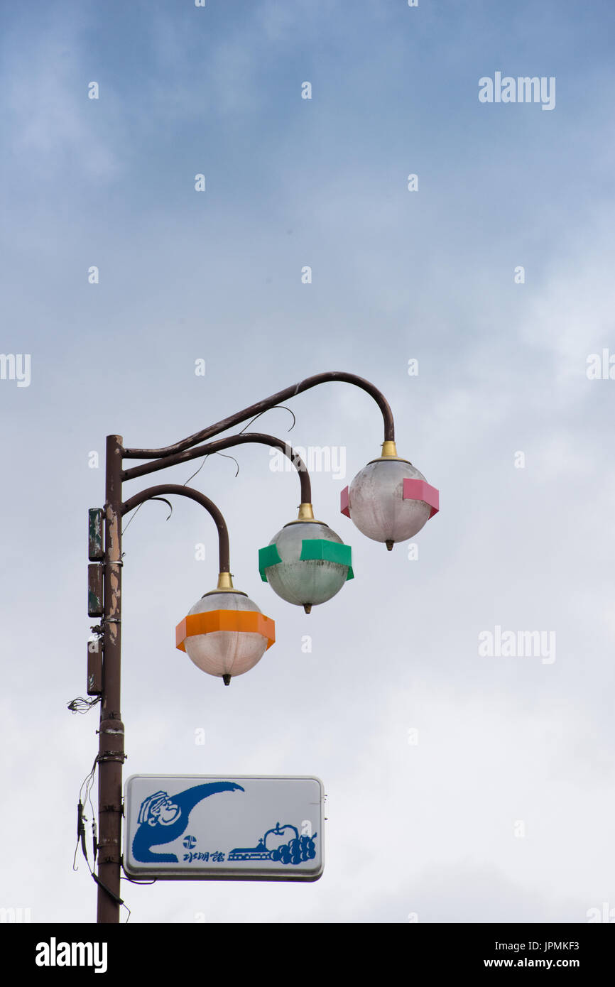 Bunt, retro Yudanaka Japan-Laterne mit einem blau-weißen Schild mit Schnee Affe und Obst. Die Befestigungen sind orange, grüne und rosa Bändern. Stockfoto