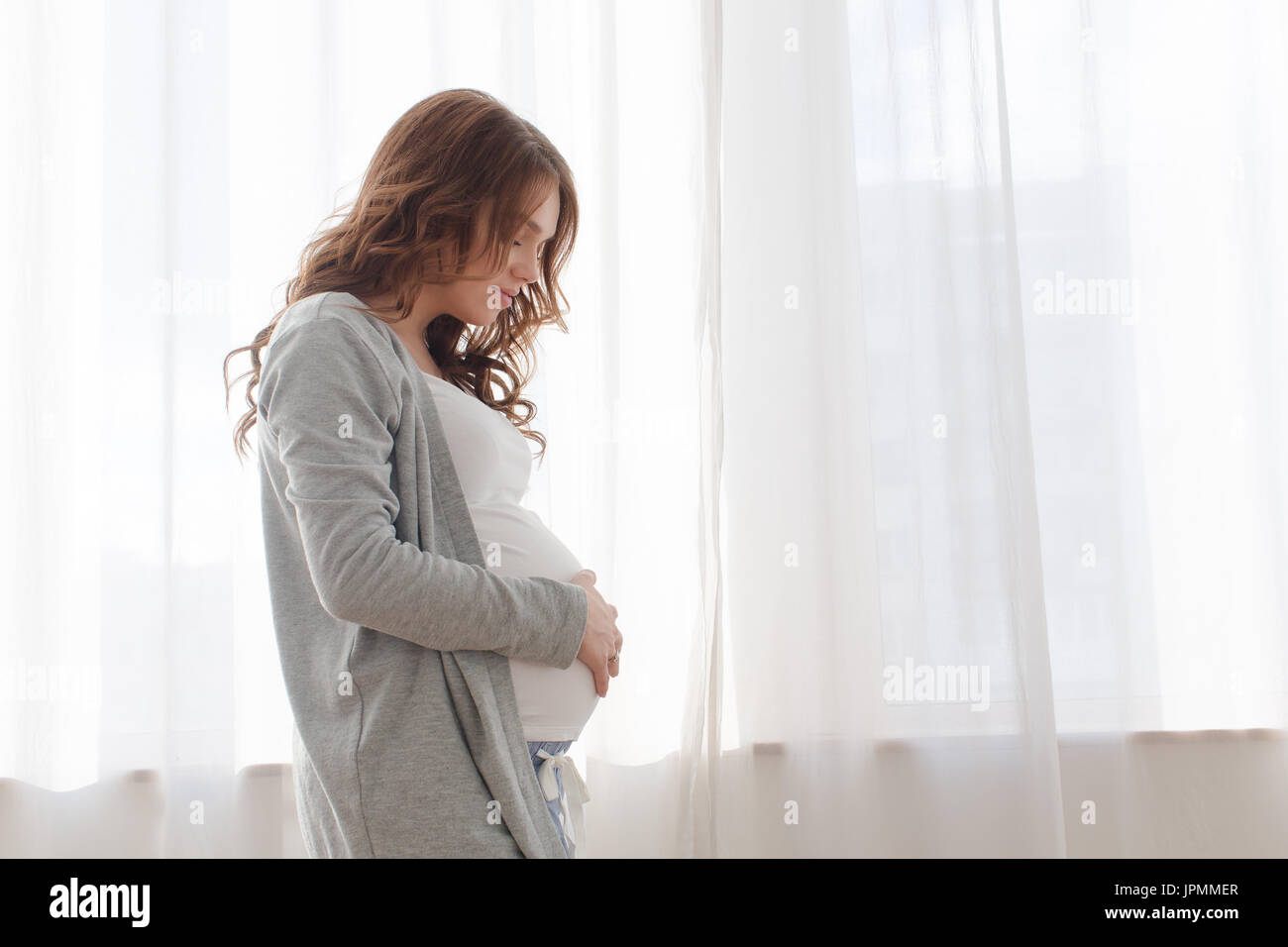 Schwangere Frau Bauch berühren auf weißem Hintergrund Stockfoto