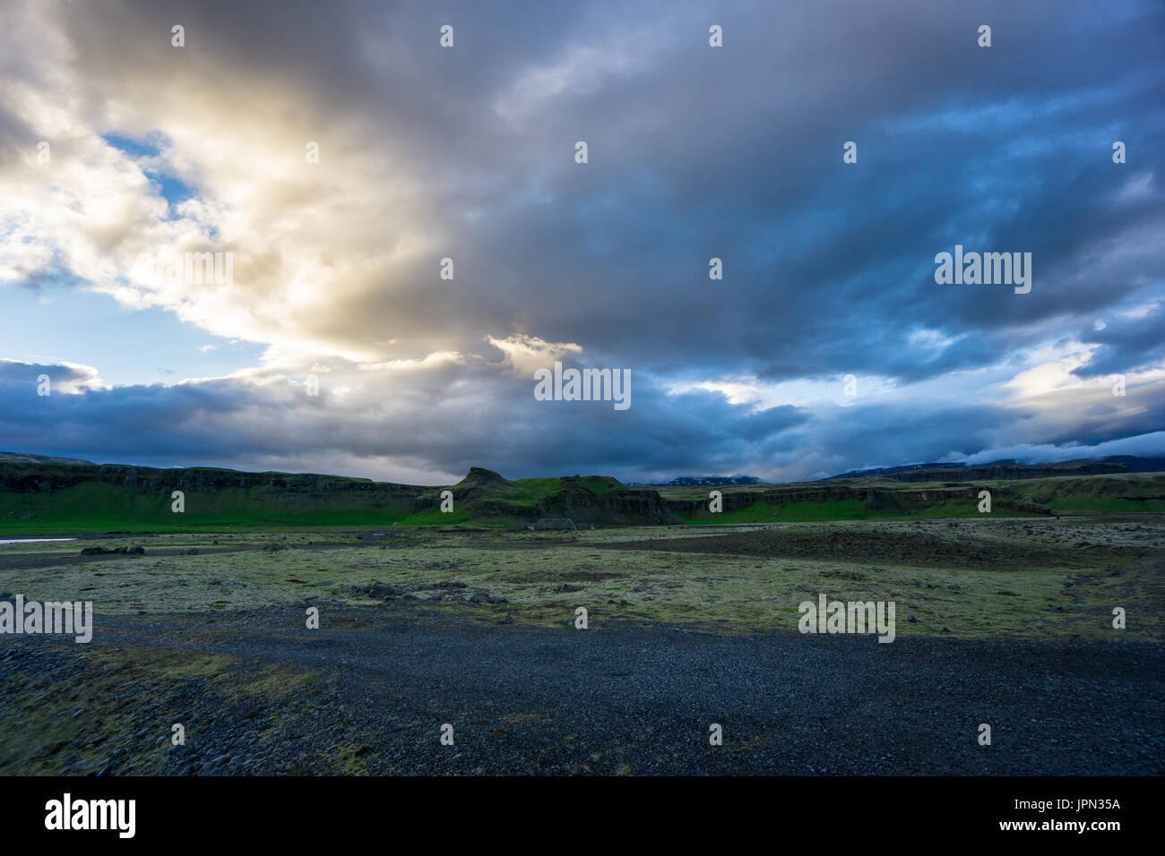 Island - Glowing bewölkten Himmel im Morgengrauen mit intensiv grünen Felslandschaft Stockfoto