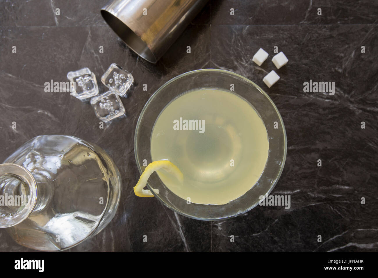 Lemon Drop Martini in stemmed Glas mit Würfelzucker, Shaker und garniert mit einem Twist Flasche flach legen. Stockfoto