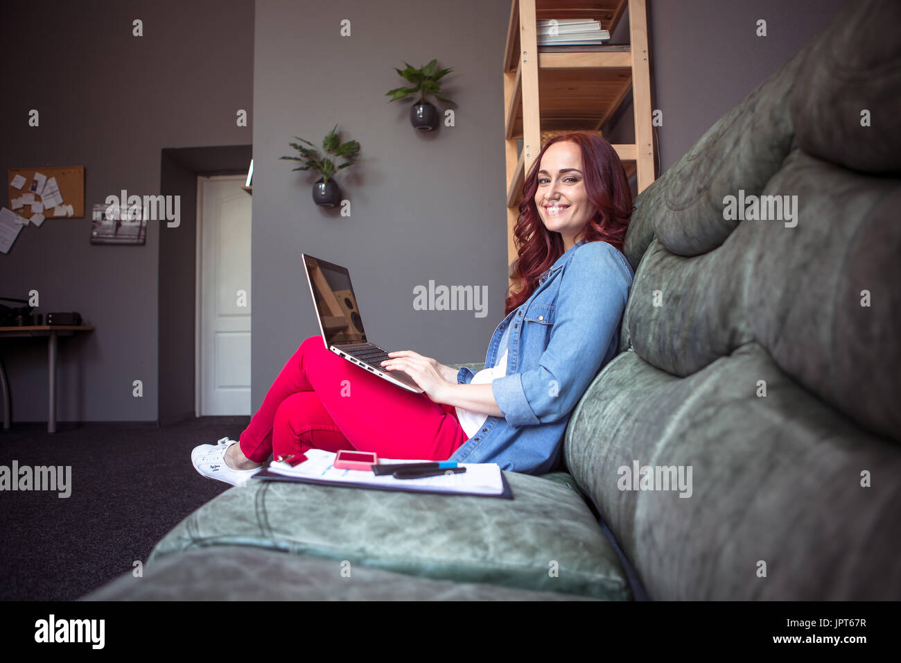 Lächelnde rote kurzhaarige Frau am Projekt von zu Hause aus arbeiten. Frelance Konzept, keine Notwendigkeit zu Büro gehen. Stockfoto