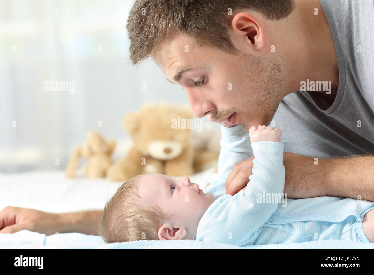 Seitenansicht eines Baby und Vater zusammen auf einem Bett spielen hautnah Stockfoto
