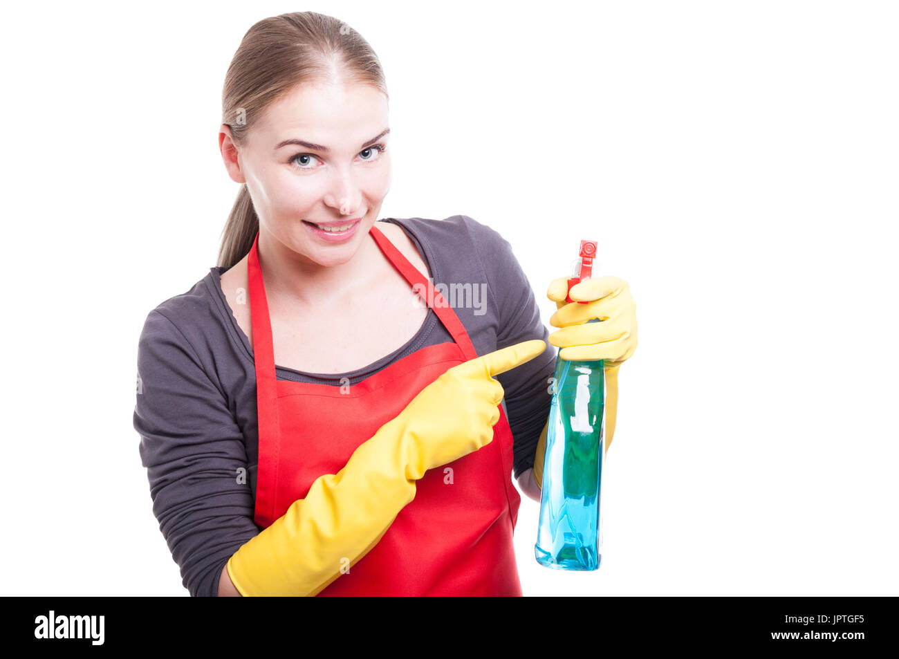 Ziemlich lächelnd Haushälterin mit Gummihandschuhe und Schürze mit Reinigungsspray Stockfoto