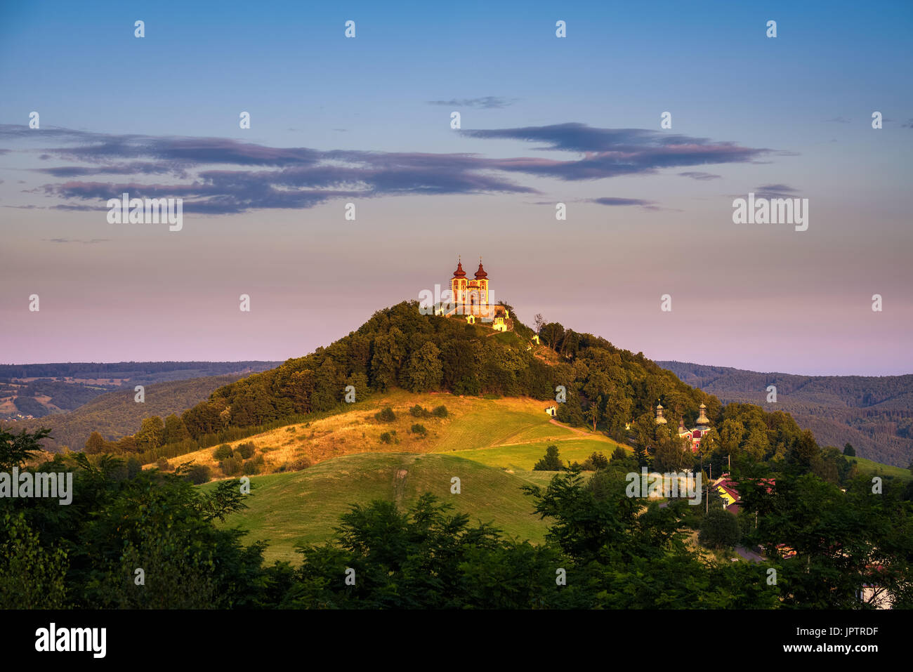 Obere Kirche mit zwei Türmen und barocken Kalvarienberg in Banska Stiavnica, Slovaka bei Sonnenuntergang. Banska Stiavnica ist eine vollständig erhaltene mittelalterliche Stadt und Stockfoto