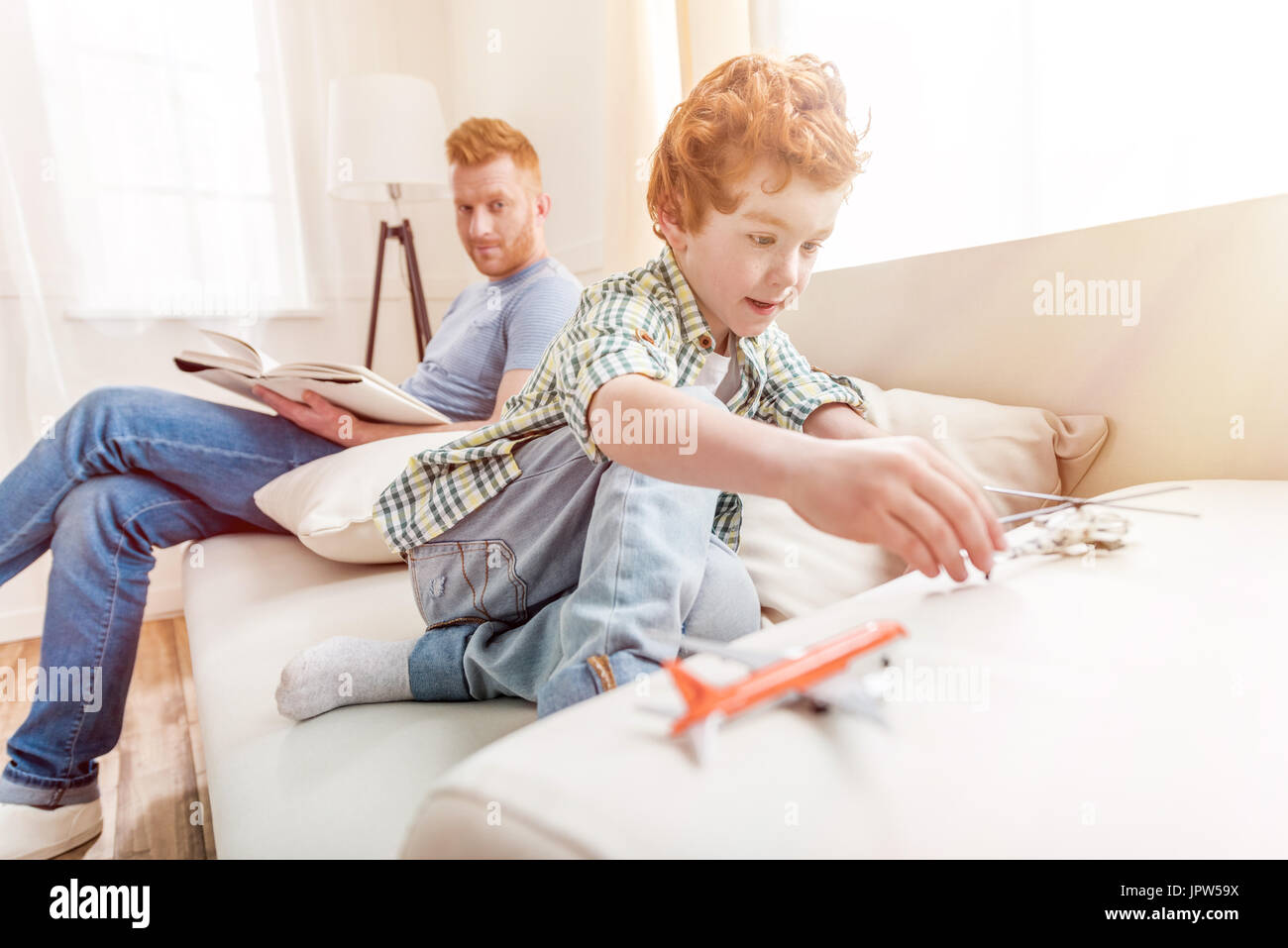 Seitenansicht des fokussierten kleiner Junge spielt mit Spielzeug mit Vater hinter Stockfoto