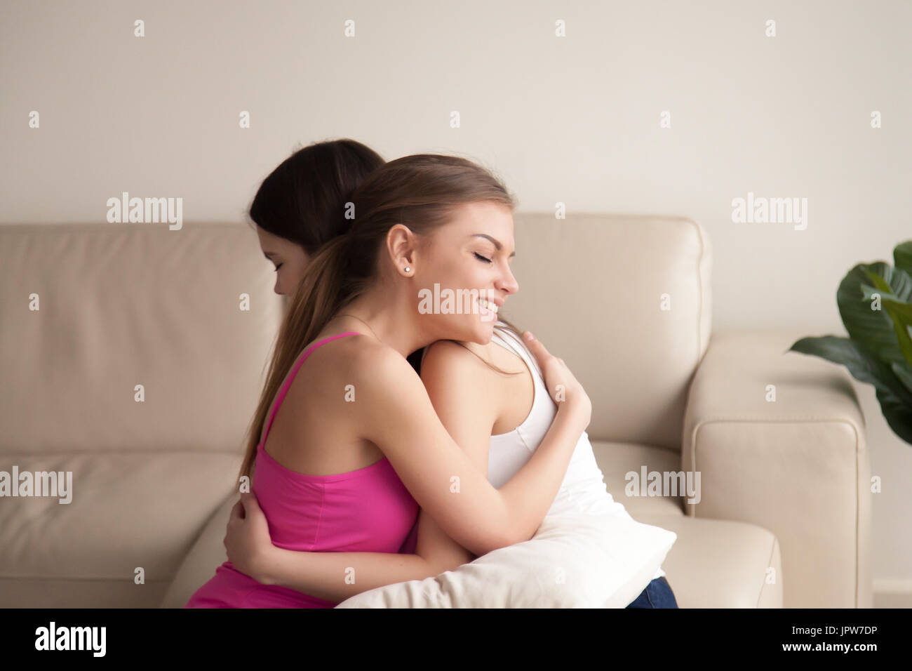 Zwei junge Frauen Freunde umarmt auf sofa Stockfoto