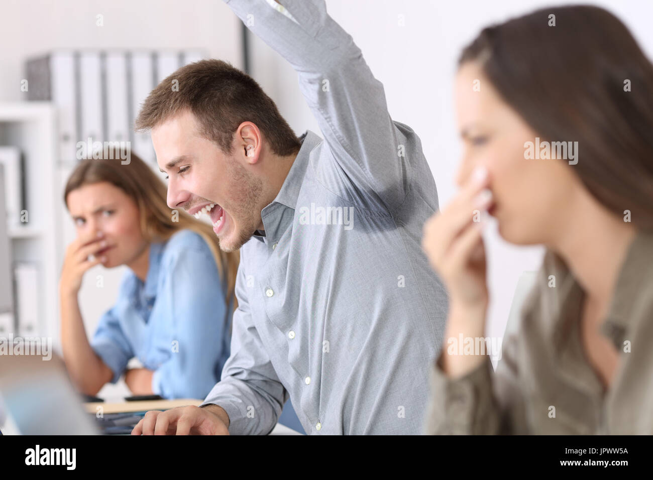 Mann zeigt eine verschwitzt und stinkig Unterarm und angewidert Kollegen im Büro Stockfoto