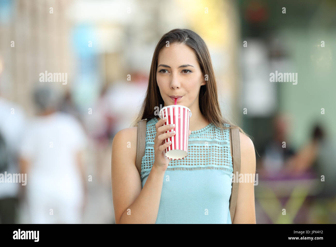 Vorderansicht Porträt einer Frau zu Fuß und eine Take-away Erfrischung auf der Straße trinken Stockfoto