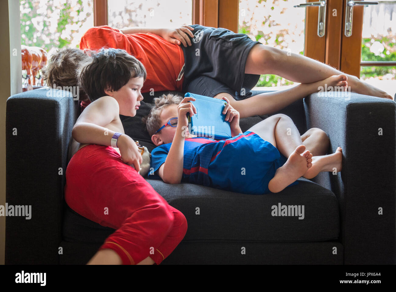 Young Boy Spielen Spiele auf dem iPad mit 2 anderen Jungen Auf der Suche nach Stockfoto