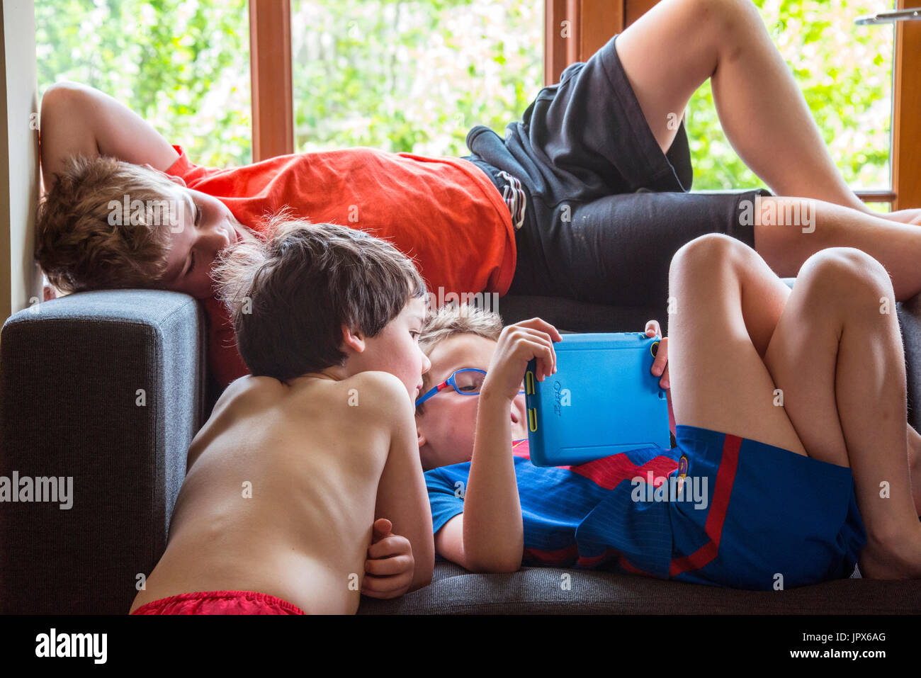 Young Boy Spielen Spiele auf dem iPad mit 2 anderen Jungen Auf der Suche nach Stockfoto