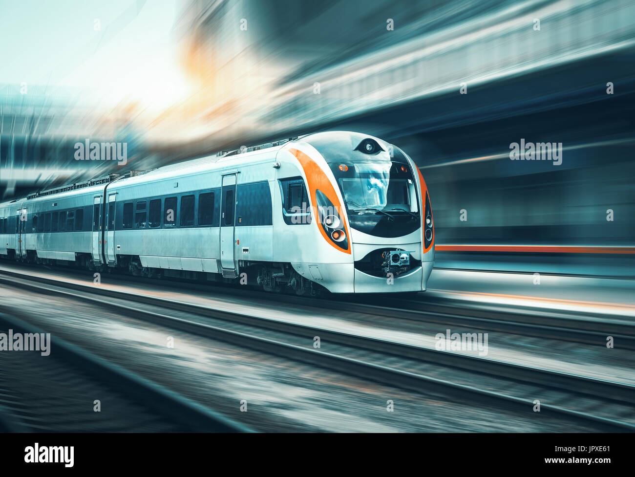 High-Speed-Zug in Bewegung am Bahnhof bei Sonnenuntergang in Europa. Modernen intercity Zug auf dem Bahnsteig mit Motion-Blur-Effekt Stockfoto