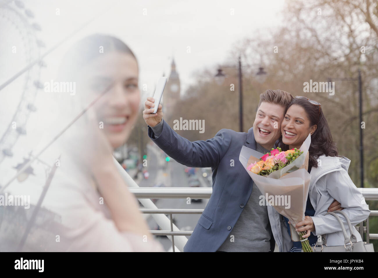 Begeisterten paar mit Blumenstrauß nehmen Selfie mit Kamera-Handy auf städtische Brücke, London, UK Stockfoto