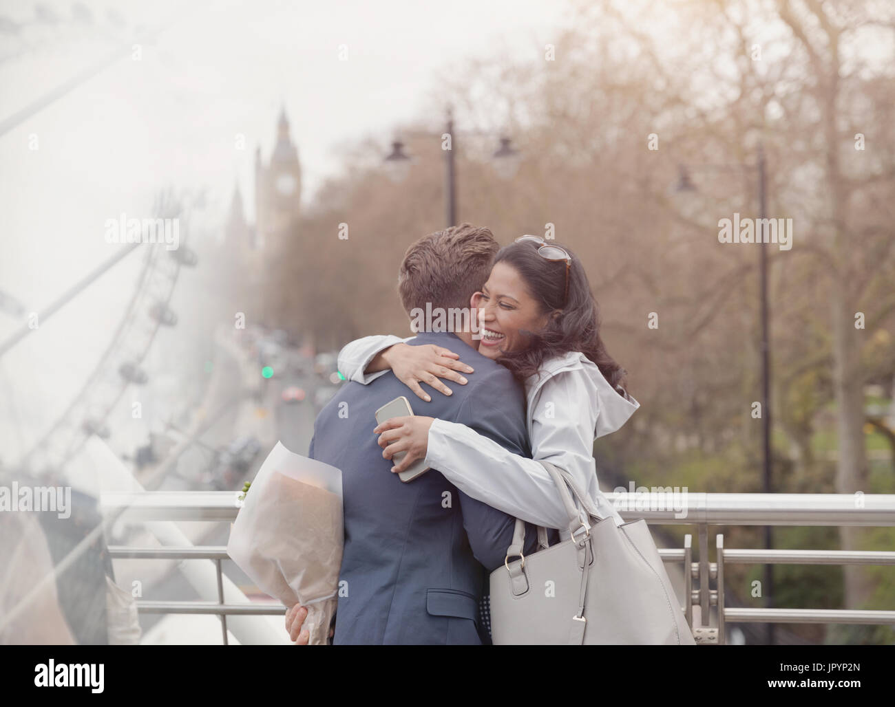 Lächeln, paar umarmt, Freund überraschend Freundin mit Blumen auf städtische Brücke, London, UK Stockfoto
