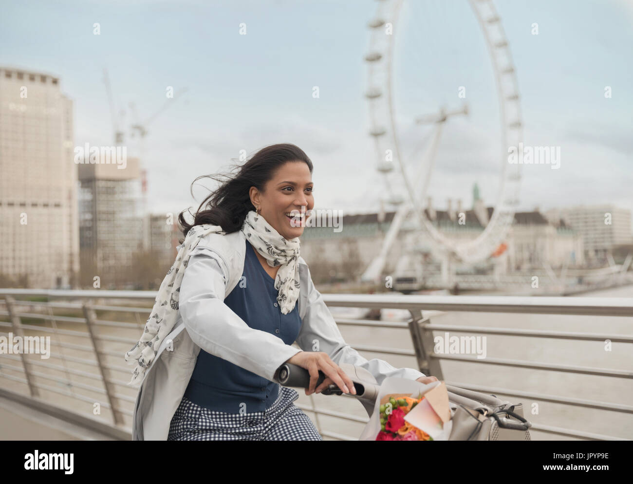Begeisterte, lächelnde Frau Radfahren auf Brücke in der Nähe von Millennium Wheel, London, UK Stockfoto