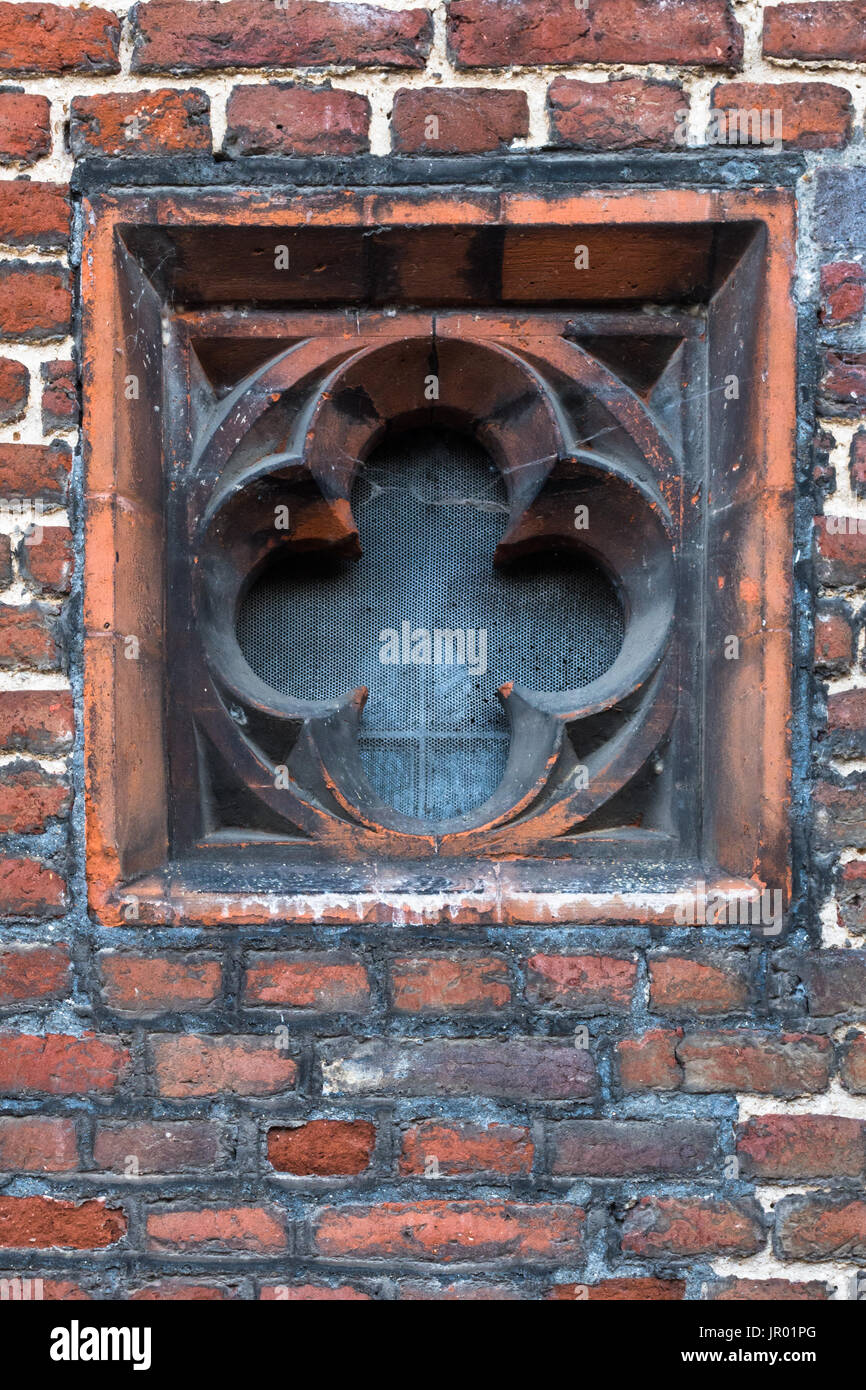 Nahaufnahme Detail des Rosen-Kreuzes geformte Fenster Schlitz in die Außenwand des Tudor Architektur Gebäude in rotem Backstein Stockfoto