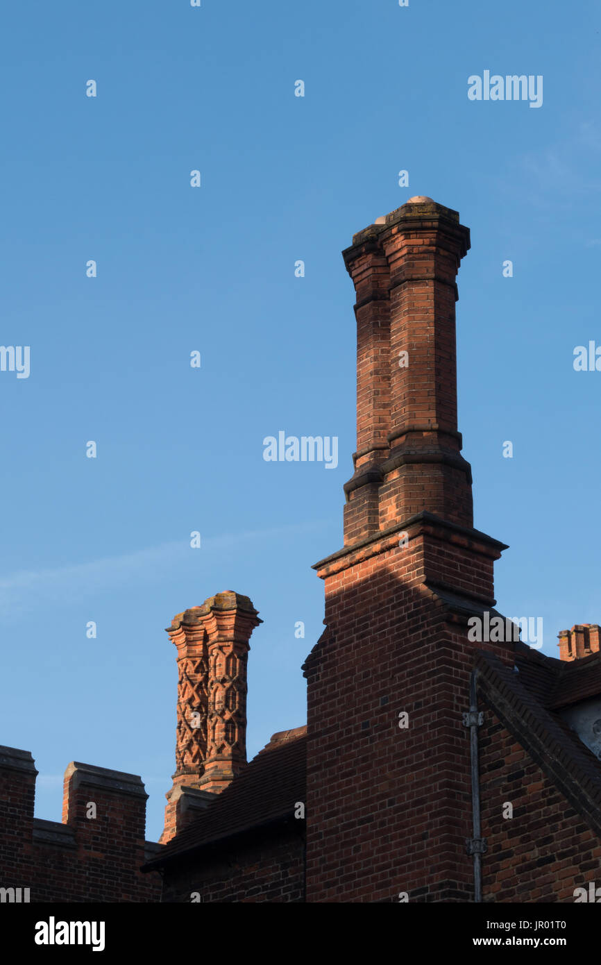 Detail der Schornsteine und Brüstung entlang des oberen Randes eine Tudor Gebäude Außenwand mit Fenster und Ornamente Stockfoto