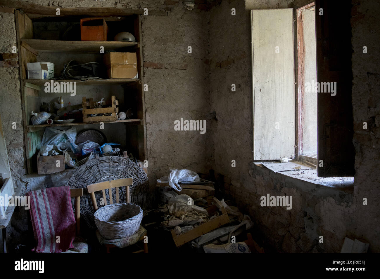 Zimmer von einer alten Hütte voller Krimskrams und erleuchtet durch ein Fenster Stockfoto