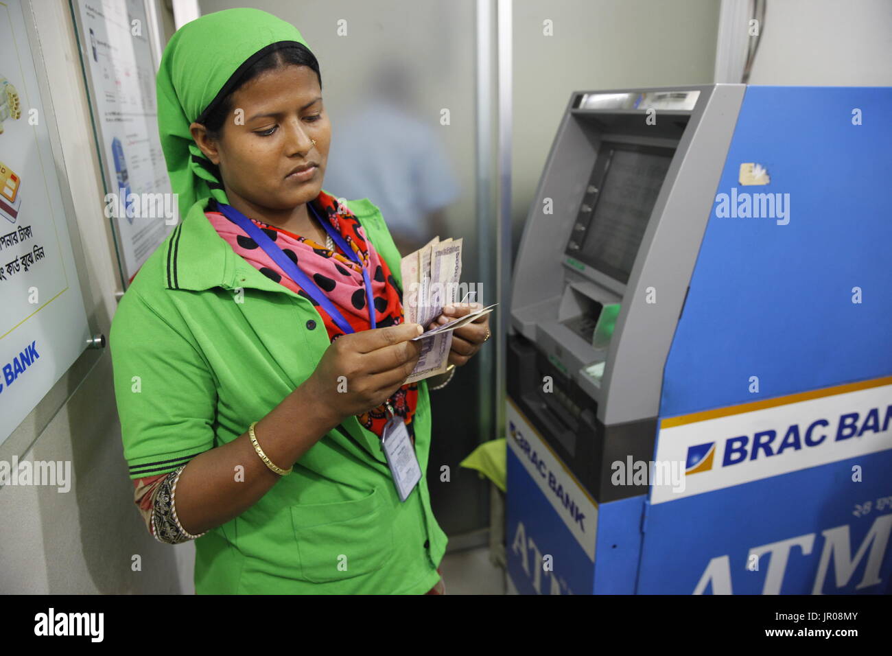 Ein fertiges Kleidungsstück Arbeiter immer Bargeld von einem Geldautomaten außerhalb einer Fabrik in Gazipur, Bangladesch am 19. April 2015. Stockfoto