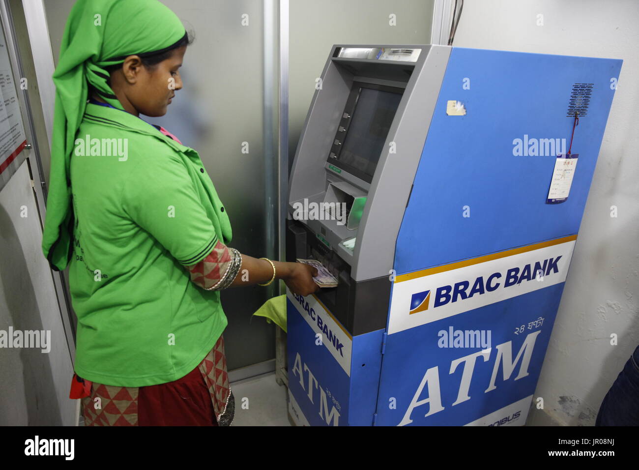 Ein fertiges Kleidungsstück Arbeiter immer Bargeld von einem Geldautomaten außerhalb einer Fabrik in Gazipur, Bangladesch am 19. April 2015. Stockfoto