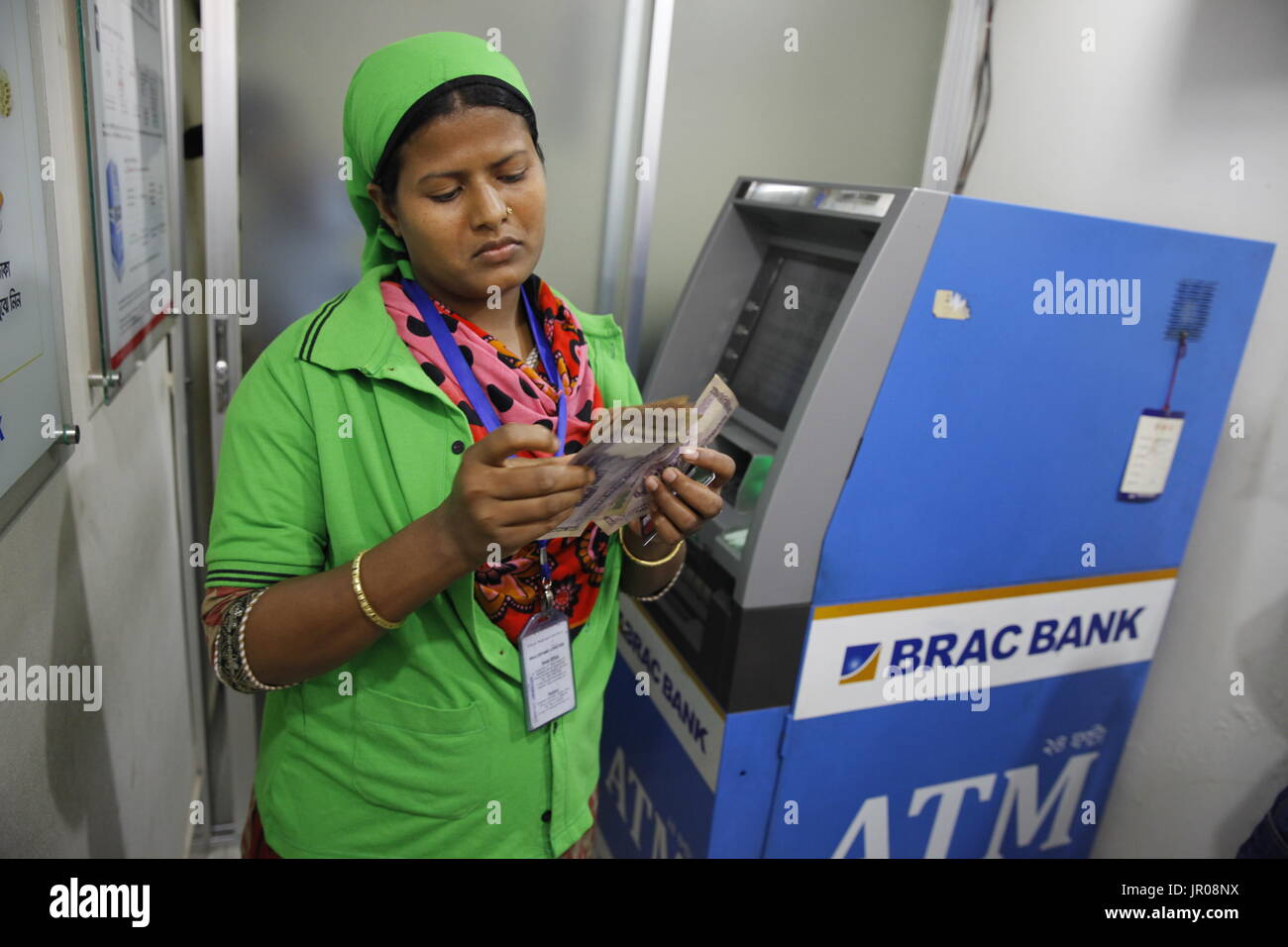 Ein fertiges Kleidungsstück Arbeiter immer Bargeld von einem Geldautomaten außerhalb einer Fabrik in Gazipur, Bangladesch am 19. April 2015. Stockfoto