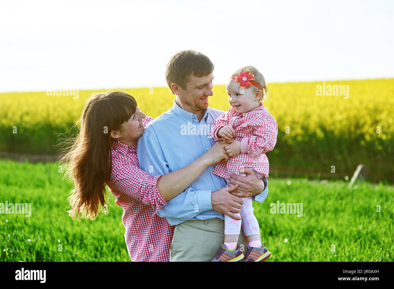 Mama und Papa und Tochter gehen auf die grünen Sommerwiese Stockfoto