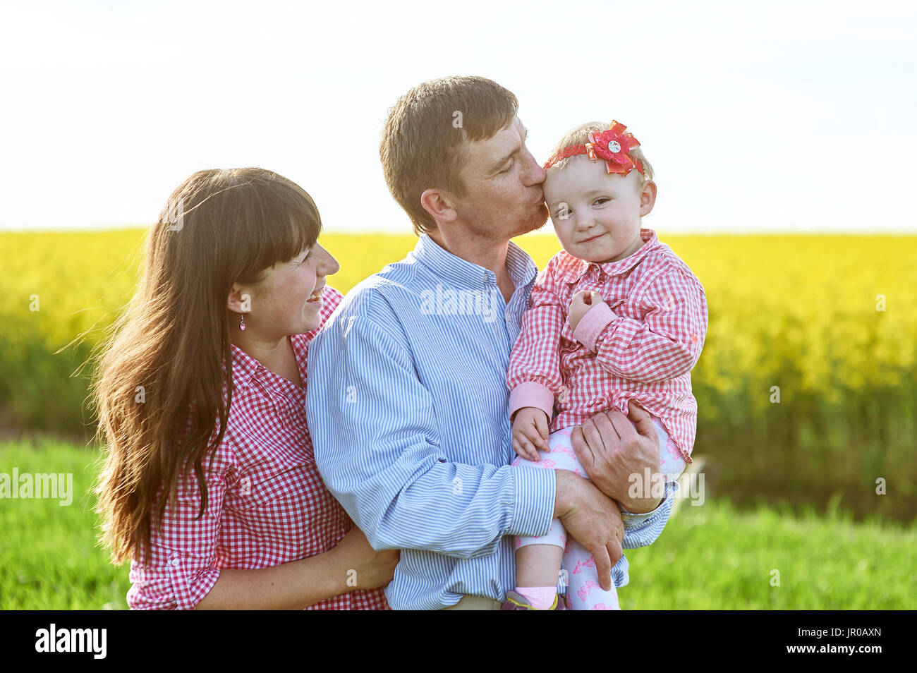 Mama und Papa und Tochter gehen auf die grünen Sommerwiese Stockfoto